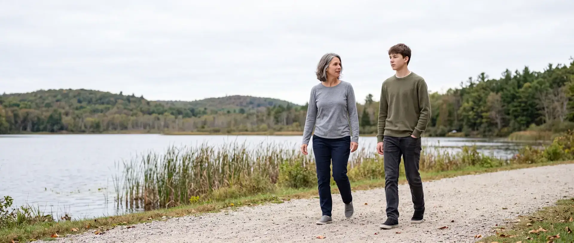 A mother and her teenage son walking a lakeside path together